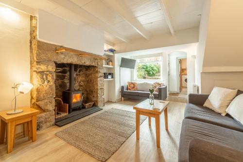 a living room with a stone fireplace and a couch at Porthgwidden Cottage in Uny Lelant