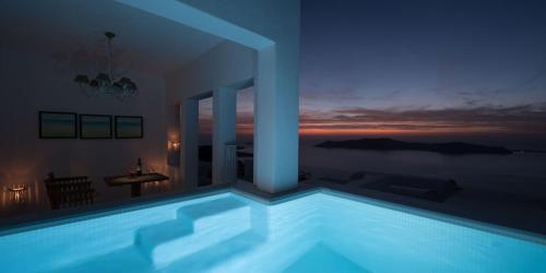 a swimming pool at night with a view of the ocean at Andromeda Villas & Spa Resort in Imerovigli