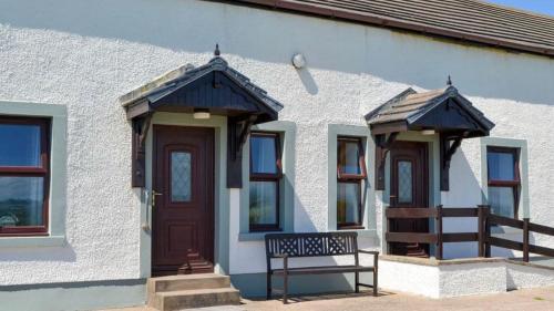 a building with a bench in front of it at Sea view cottage in Allonby