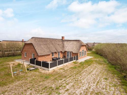 uma casa antiga com um telhado de palha num campo em 16 person holiday home in Ulfborg em Ulfborg