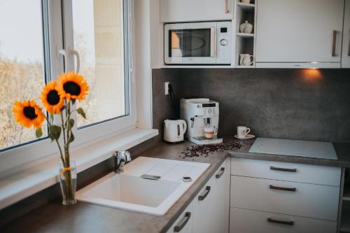 uma cozinha com um lavatório e um vaso de girassóis em Apartmán Tatranská Lomnica em Tatranská Lomnica