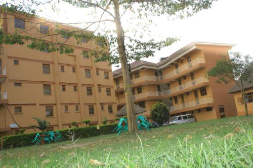 an apartment building with a tree in front of it at Pride Travellers Hotel Mubende in Mubende