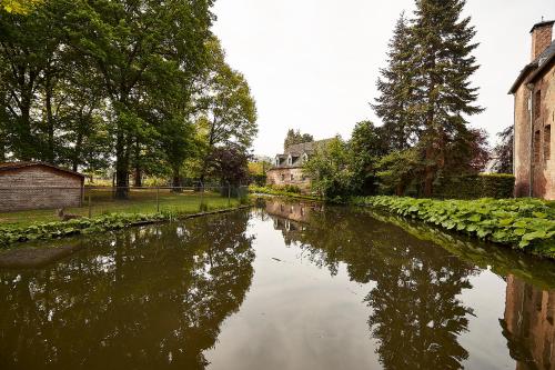 a river with houses and trees in a city at Het Knechthuys in Baarlo