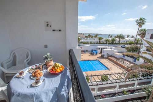 una mesa con un bol de fruta en el balcón con piscina en Casa Coral with sea views & AC, en Puerto del Carmen
