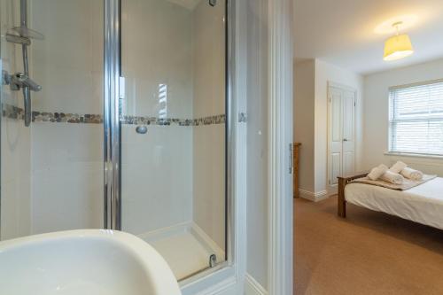 a bathroom with a shower and a sink and a bed at Porthia in Hayle