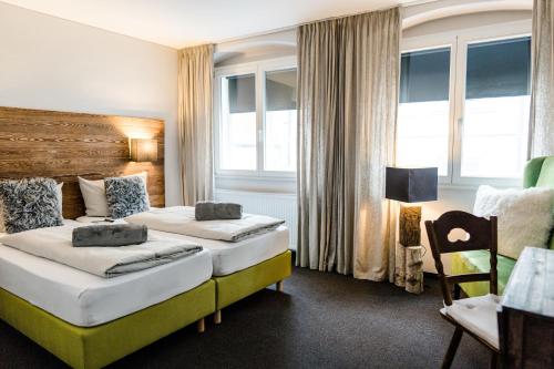 a hotel room with two beds and a chair at Hotel Goldene Steig in Kempten