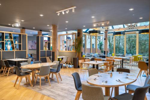 a restaurant with tables and chairs and windows at Holiday Inn Hemel Hempstead M1, Jct. 8 by IHG in Hemel Hempstead