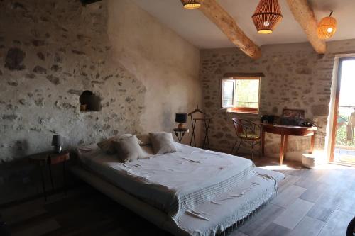 a bedroom with a large bed in a room with stone walls at tempepailla in Roynac