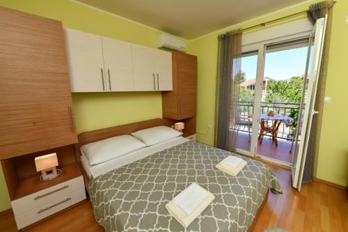 a bedroom with a bed and a balcony with a table at Apartments Vila Miranda in Vodice