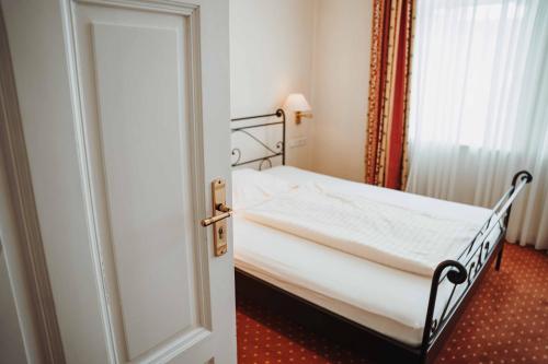 a small bed in a room with a door at Hotel am Wallgraben in Brilon