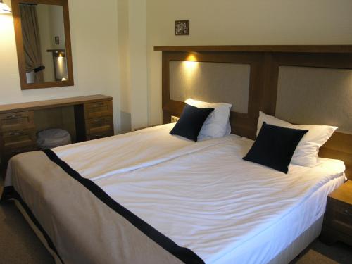 a bedroom with a large white bed with black pillows at 7 Pools SPA Boutique Hotel in Bansko