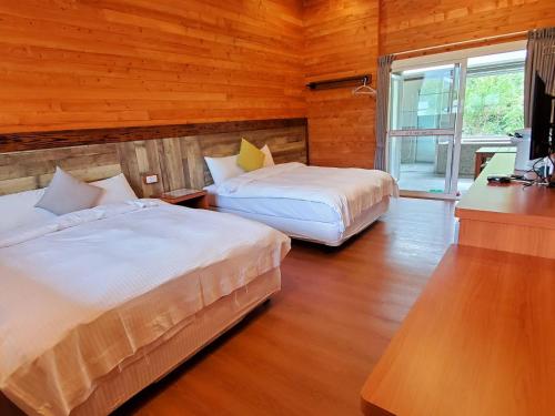 a bedroom with two beds and a desk and a television at YingChia SPA Homestay in Luye
