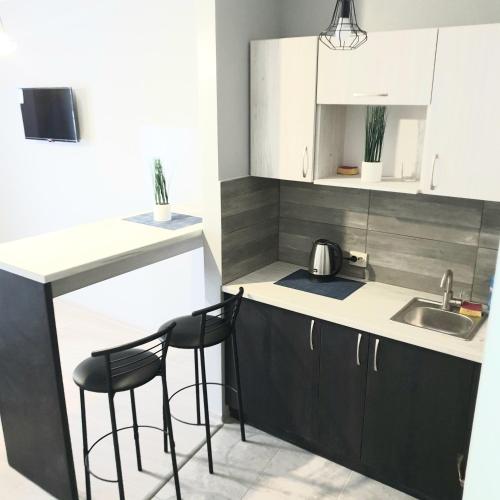 a kitchen with black and white cabinets and stools at Belvederska apartment 2 in Ivano-Frankivsʼk