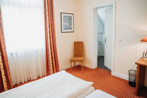 a bedroom with a bed and a chair and a mirror at Hotel am Wallgraben in Brilon