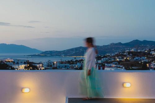 a man standing on a ledge looking out over a city at Aether Boutique Stay in Glastros