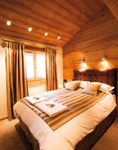 une chambre avec un grand lit avec un plafond en bois dans l'établissement Valdez Suite, à Morzine
