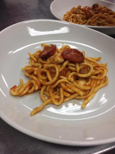 a white plate of spaghetti on a table at BASE CAMP alpine apartments in Breuil-Cervinia