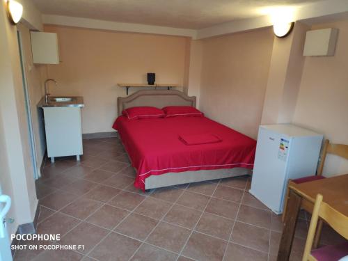 a bedroom with a bed with red sheets and a refrigerator at Apartman Pavle 2 in Virpazar