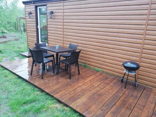 a wooden deck with a table and chairs and a grill at Miodowy Zakątek Całoroczne Domki i Pokoje przy Suntago, Deepspot, Pyszne Śniadania, Grill in Mszczonów