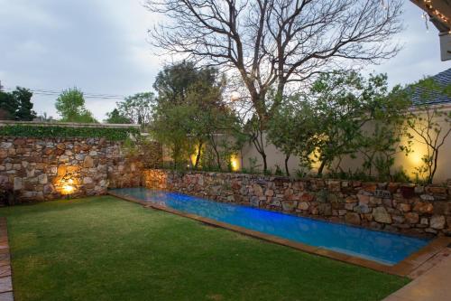 a backyard with a stone wall and a swimming pool at The Parkwood in Johannesburg
