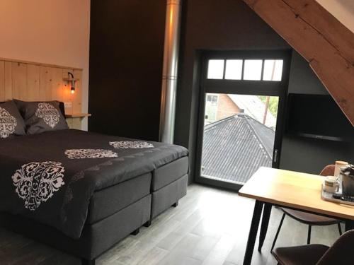 a bedroom with a bed and a table and a window at De Hostee in Stolwijk