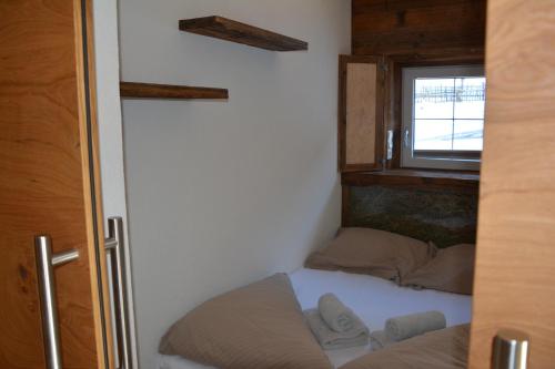 Cama pequeña en habitación pequeña con ventana en Untersillerhof, en Neustift im Stubaital