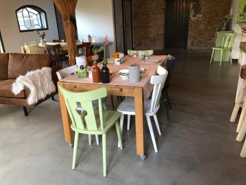 a wooden table with four chairs and a couch at De Hostee in Stolwijk