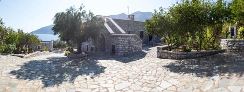 a house with a stone courtyard with trees and a building at Skoutari Bungalows Galateia room in Skoutarion