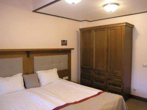 a bedroom with a bed and a wooden cabinet at 7 Pools SPA Boutique Hotel in Bansko