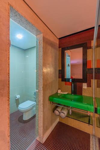 a bathroom with a green sink and a toilet at Spa urbano Motel Adult Only in Fortaleza