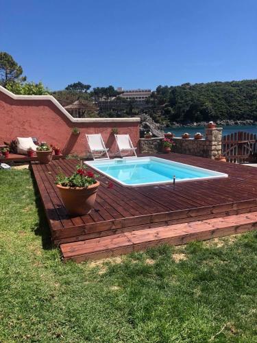 a swimming pool on a wooden deck next to a house at Yiannis Seafront Villa Paleokastritsa in Paleokastritsa