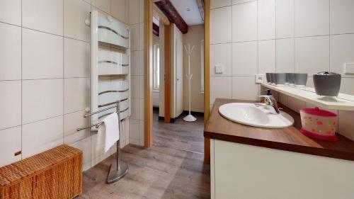 une salle de bain blanche avec un lavabo et un miroir dans l'établissement Aux Bijoux De Colmar - 1 Parking Gratuit, à Colmar