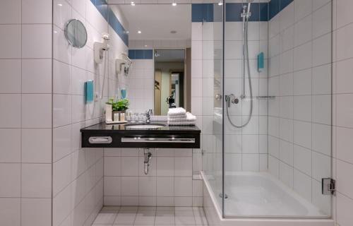 een badkamer met een douche, een wastafel en een bad bij Tulip Inn Hotel Düsseldorf Arena in Düsseldorf