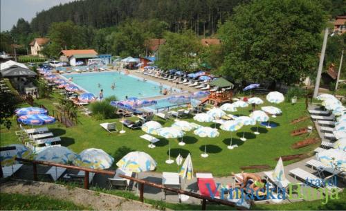a large pool with a bunch of umbrellas and chairs at Relax Apartment in Vrnjačka Banja