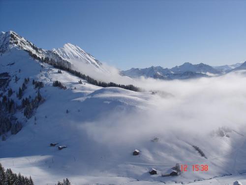 a view of a snowy mountain with a layer of clouds at Hotel Jägerstüble in Damuls
