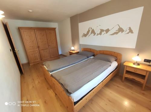 a bedroom with a wooden bed with two night stands at Residence Montebel in Tesero