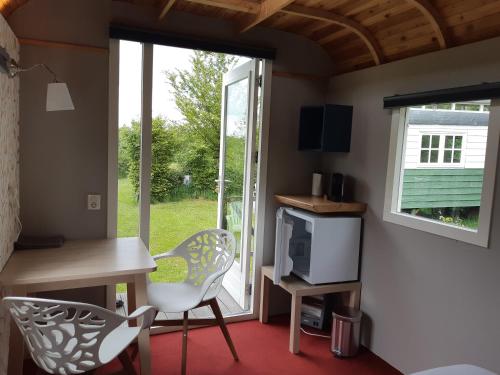 a room with a desk and chairs and a window at B&B Pipowagen "het Wellnesst" op Wellness Camping en B&B Stoltenborg in Meddoo