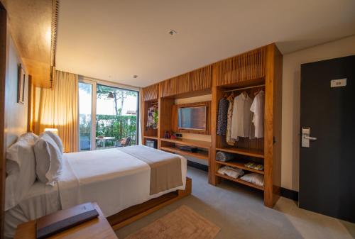 um quarto com uma cama, uma televisão e uma janela em Hotel Spa Nau Royal em Camburi