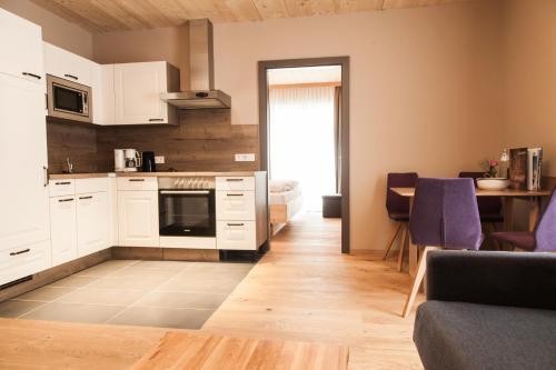 a kitchen with white cabinets and a living room at Friedlwirt-Kraftplatz Natur in Unken