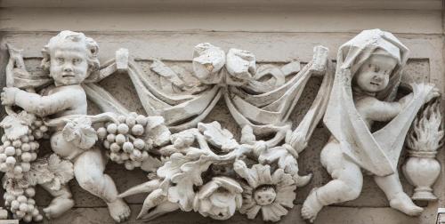 een standbeeld van twee cherubs en fruit op een muur bij Hotel Fregehaus in Leipzig