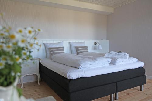 a bed with white sheets and pillows in a bedroom at Kallehavegaard Badehotel in Løkken