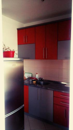 a kitchen with red cabinets and a black refrigerator at Spa apartman Iva in Banja Luka