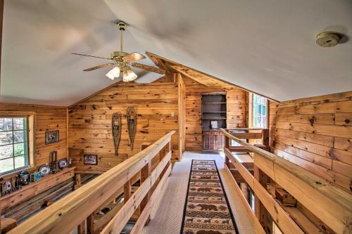 a log cabin with a ceiling fan and wooden walls at Spacious Mtn Cabin on 7 Private Acres in Athol! in Athol