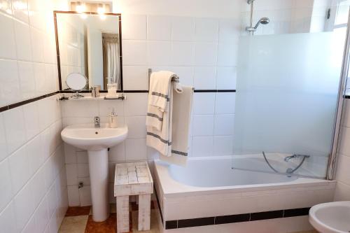 a white bathroom with a sink and a tub and a toilet at Casa Vale Del Rei in Tavira