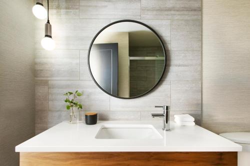 a white sink sitting under a mirror in a bathroom at Kimpton - Armory Hotel Bozeman, an IHG Hotel in Bozeman