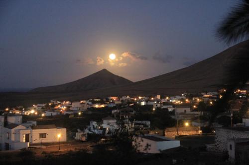 a full moon rising over a city at night at Casa Yahshua in Villaverde