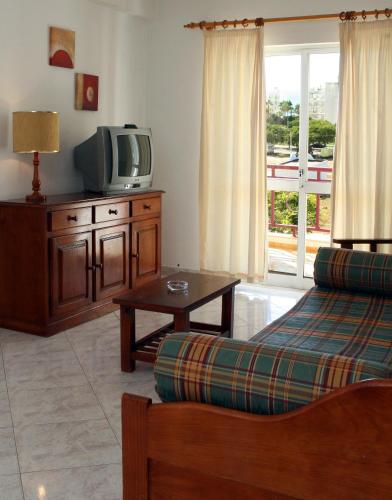 a living room with a couch and a tv at Apartamentos King's in Quarteira
