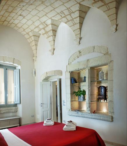 a bedroom with a red bed and a mirror at Dimora Storica La Torre Nel Borgo in Borgagne