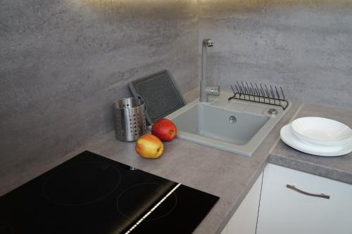 a kitchen with a sink and apples on a counter at Apartament Gliwice Centrum Dunikowskiego z garażem in Gliwice