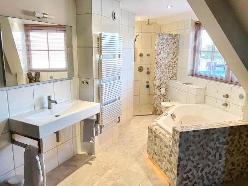 a bathroom with a tub and a sink and a shower at Villa Pura Vida in Oud-Ade